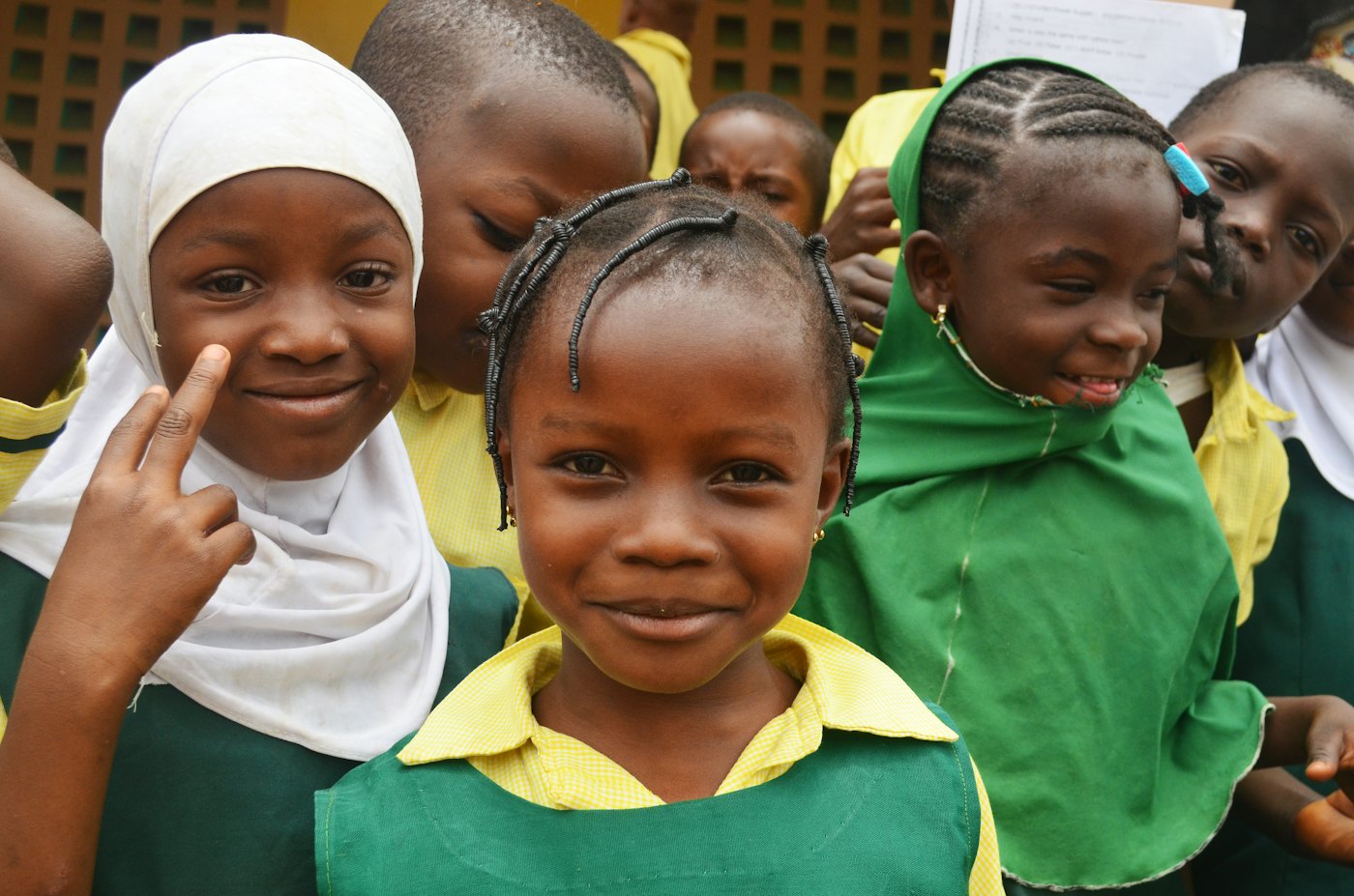 Smiling pupils in green and yellow school uniforms